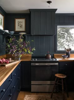 a kitchen with dark blue cabinets and wooden counter tops