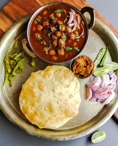 a plate with some food on it next to a bowl of soup and breads