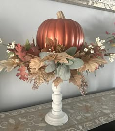 a white vase filled with flowers and leaves on top of a table next to a mirror