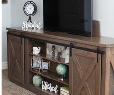 a flat screen tv sitting on top of a wooden entertainment center next to a clock