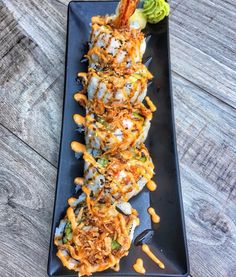 a black plate topped with food on top of a wooden table