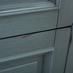 a close up view of the handles and drawers on a gray kitchen cabinet with brown stains