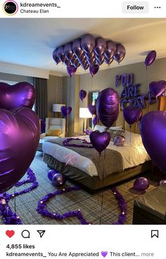 purple balloons floating in the air over a bed