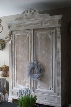 an old white armoire with wreaths on it