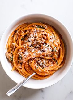 a white bowl filled with pasta and topped with parmesan cheese