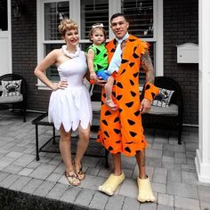 a man and woman are dressed up as flint the cat and his wife pose for a photo in front of their house