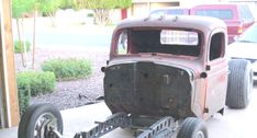 an old car is being worked on in a garage with other cars and trucks behind it