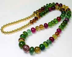 "Thank you for coming in! A Spectacular necklace made of smooth tourmaline plain rondelle beads with mesmerizing charm and 18k solid yellow gold plain beads! The stones come in shaded rubellite pink, verdilite green, indicolite blue, golden yellow color, amazing colors, extremely rare transparent material and hard-to-find huge sizes! 26\" individually knotted necklace, symmetrical arrangement on both sides with a 15mm focal bead! 545.25 carats for the tourmaline alone! 26 inches long! You'll get Elegant Tourmaline Round Beaded Necklaces, Elegant Tourmaline Beaded Necklaces With Round Beads, Elegant Tourmaline Beaded Necklaces, Golden Yellow Color, Knotted Necklace, Yellow Gold Necklace, Transparent Material, Colorful Feathers, Knot Necklace