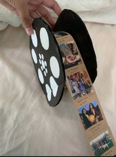 a person is holding a black ribbon with white paw prints on it and there are pictures attached to it