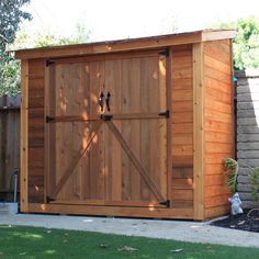 a large wooden shed sitting in the middle of a yard next to a tree and fence