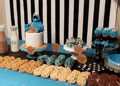 a table with cookies, cookies and cupcakes on it in front of a black and white striped wall