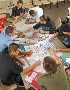 a group of people sitting around a table writing on paper