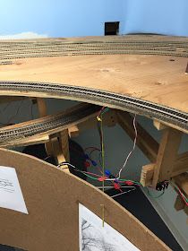 a model train set is being built on top of a cardboard box and some wires are plugged into the board