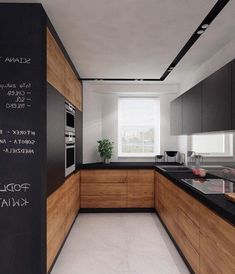 a kitchen with black counter tops and wooden cabinets, along with chalk writing on the wall