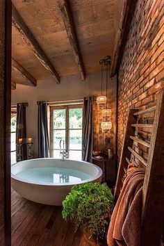 a bathroom with a large bathtub and wooden flooring next to a brick wall