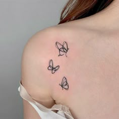 three butterflies tattoo on the back of a woman's shoulder