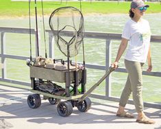 a woman is pulling a cart with fishing gear on it