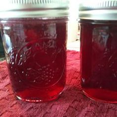 two jars filled with red liquid sitting on top of a pink tablecloth covered floor