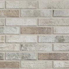 a white brick wall with grey and brown bricks