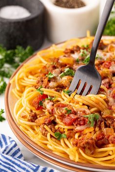 a fork is stuck into a plate of spaghetti with meat sauce and parmesan cheese