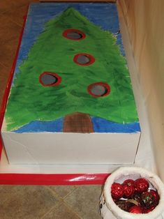 a decorated christmas tree sitting on top of a box next to a bowl of fruit