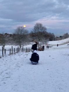 a person riding a snowboard down a snow covered road next to a wooden fence