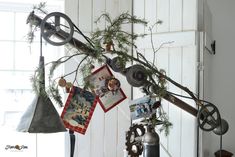 an old clock hanging from the side of a white wall next to bells and pictures