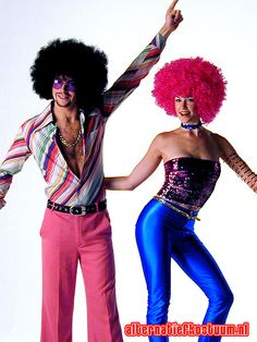 two people dressed in costumes and wigs posing for the camera with their arms outstretched