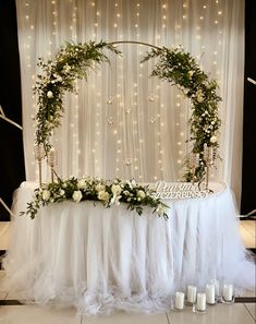 a table with flowers and candles on it in front of a curtained backdrop that has lights