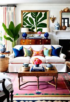 a living room filled with lots of furniture and colorful pillows on top of a rug