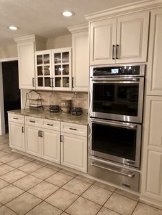 a large kitchen with white cabinets and stainless steel appliances in the middle of tile flooring