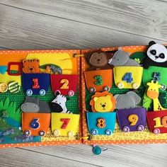 an open children's book with felt animals and numbers on the pages, sitting on a wooden floor