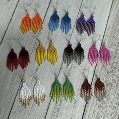 several pairs of multicolored beaded earrings hanging from hooks on a wooden surface