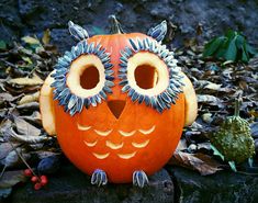 an orange owl pumpkin sitting on top of leaves