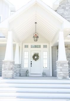 a white front door with a wreath on it and steps leading up to the entrance