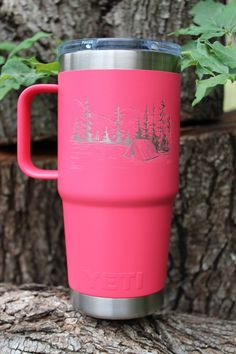 a pink cup sitting on top of a tree stump next to a plant in front of it