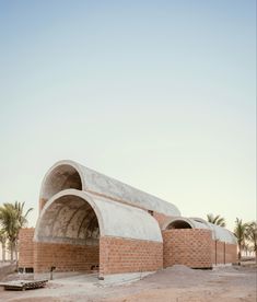 an old brick building with arches on the side and palm trees in the back ground