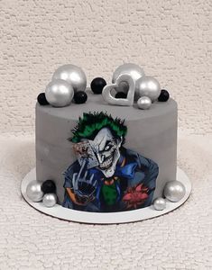 there is a cake decorated with a joker face on the top and silver balls around it