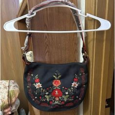 a handbag hanging on a door handle in front of a wooden door with floral designs