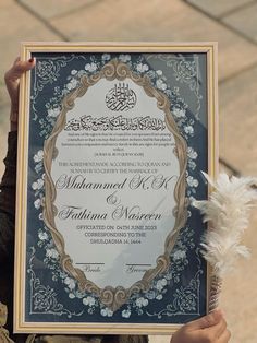 a person holding up a certificate in front of their face and the frame is decorated with flowers