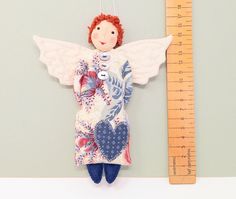 an angel ornament hanging on a wall next to a ruler