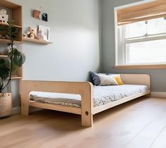 a bed sitting in the middle of a room next to a window with wooden shelves