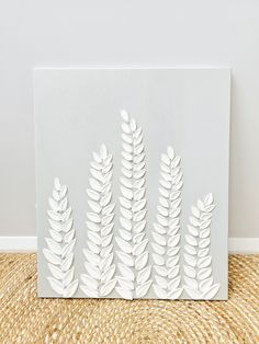 a white paper cut out of leaves on top of a straw mat next to a wall