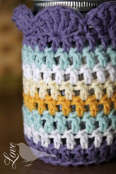 a crocheted jar is sitting on a table with a can holder in it