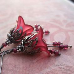 two red flower brooches sitting on top of a pink cloth covered tablecloth