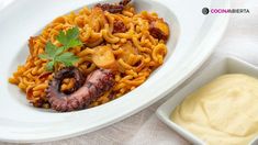 pasta with meat and vegetables in a white bowl next to a container of mayonnaise