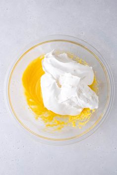 a glass bowl filled with whipped cream and orange zest on a white table top