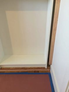 an empty shelf in the corner of a room with blue tape on the floor next to it