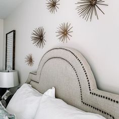 a bed with white sheets and pillows in front of three starbursts on the wall