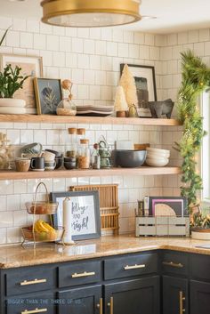 a kitchen with black cabinets and white subway backsplash, gold trim around the shelves